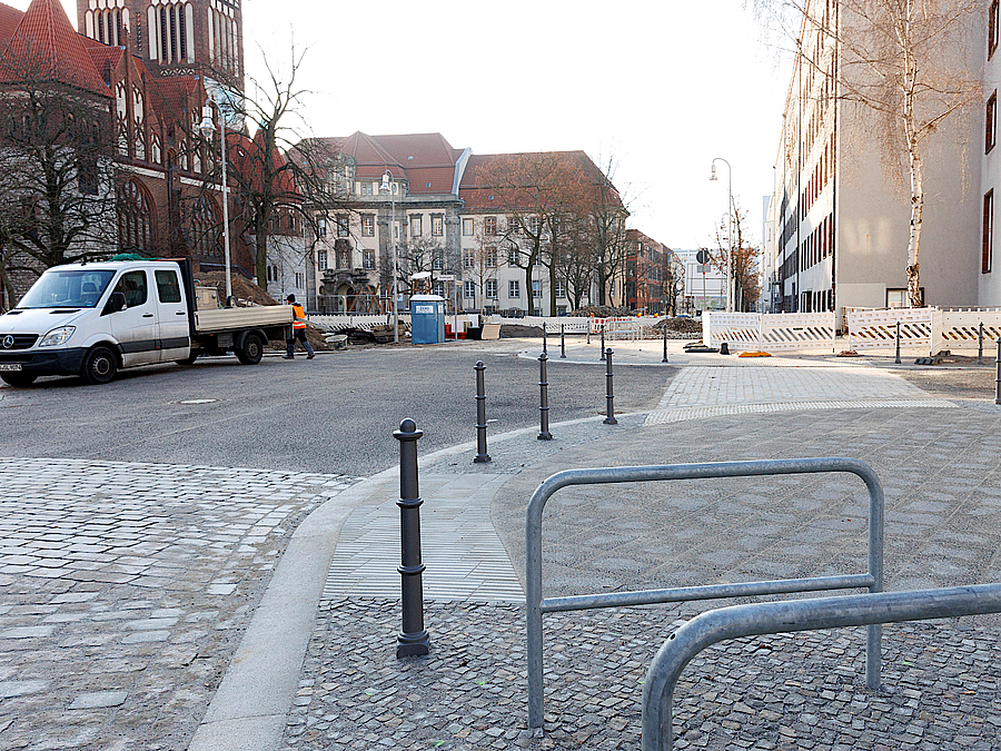Straße, Fußweg mit Metallpollern und Fahrradbügeln, Baken, Baufahrzeug, Kirche