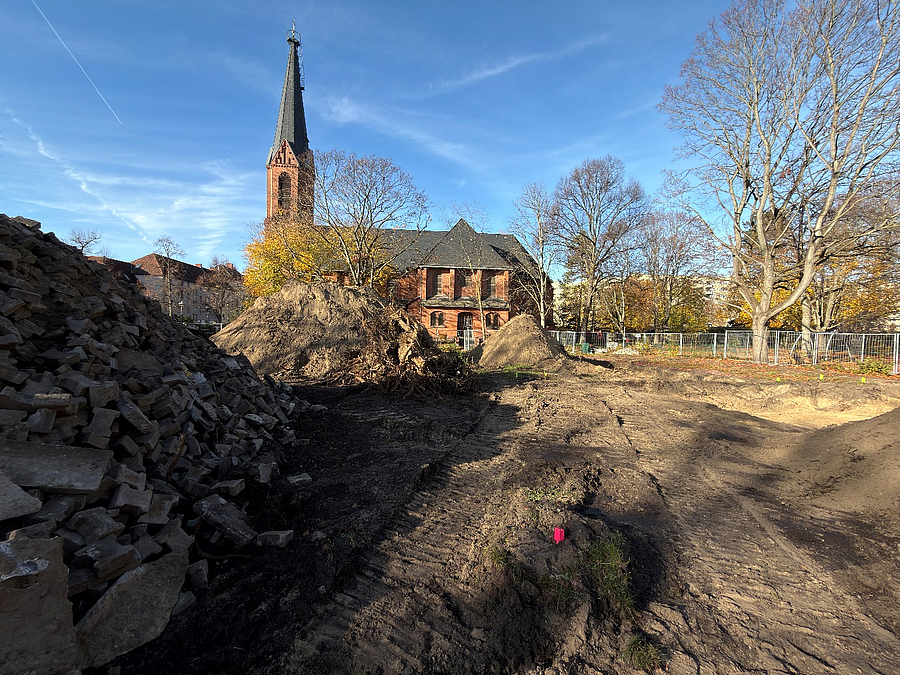 Kirche im Winter, davor große Bauschutt- und Erdhaufen