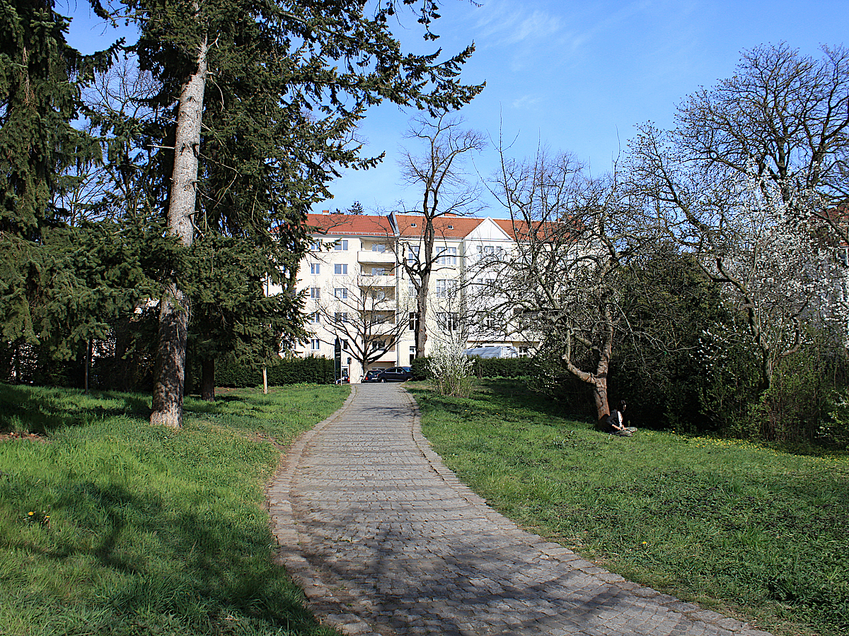 Weg zwischen Nadel- und Obstbäumen auf Wohnhaus zu
