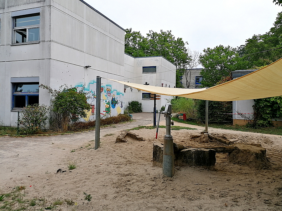 Der Wasserspielplatz erhält einen Sitzwall als Einfassung Kleine Sandfläche mit Pumpe und Sonnensegel