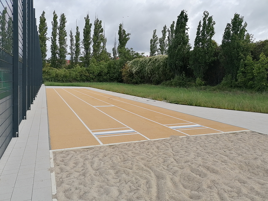 Weitsprunganlage, Ballfangzaun, Grün im Hintergrund