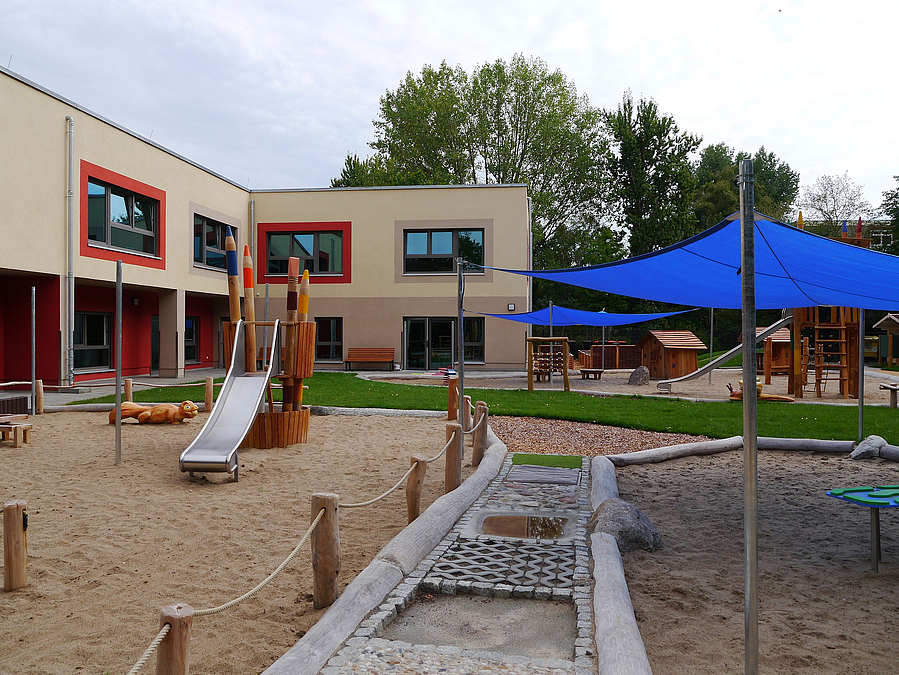 Gebäude-Ecke, Spielgarten, blaues Sonnensegel, Tastpfad