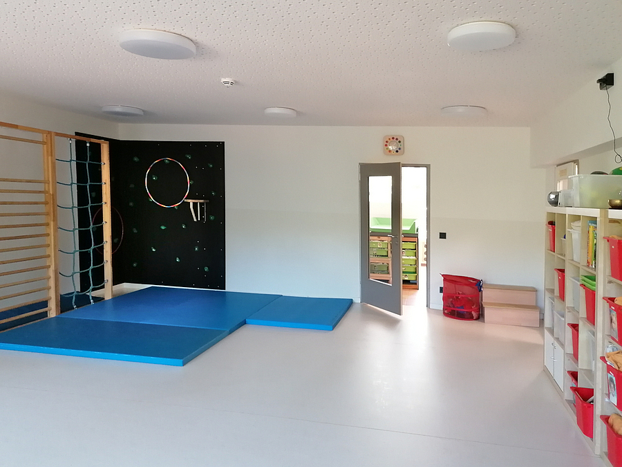 großer, heller Raum mit Kletterwand, Sprossenwand, Matten und Regalen