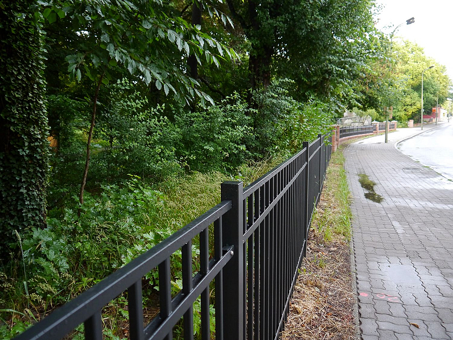 Blick entlang der erneuerten Einfriedung in Richtung Tor