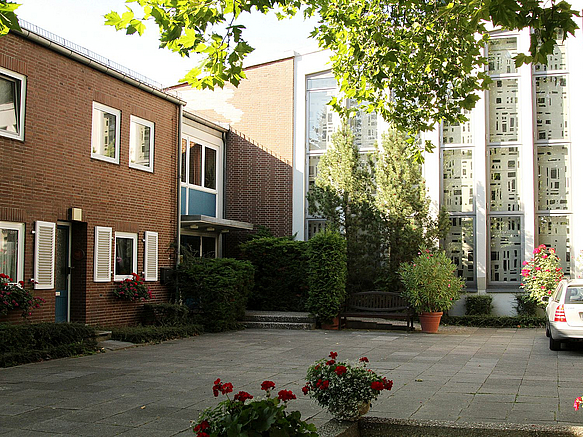 Hof mit Backsteingebäude und vertikal durchgängigen Kirchenmosaikfenstern