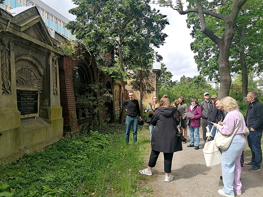 Gruppe vor Grabmalen in Backsteinmauer