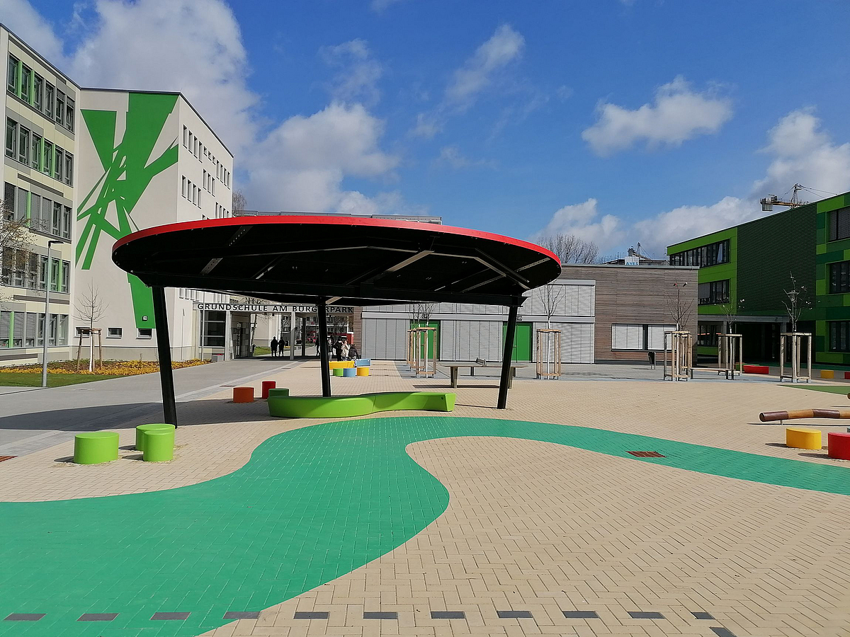 Schulgebäude, Pavillon mit ovalem Dach, grünes Band auf gepflastertem hof