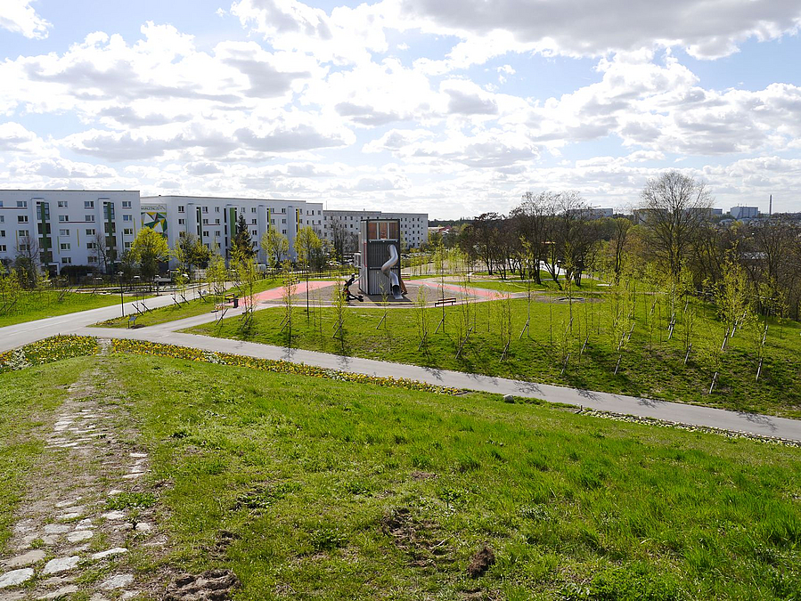 Totale über Wiesen auf Plattenbaugebeit, davor Spielplatz