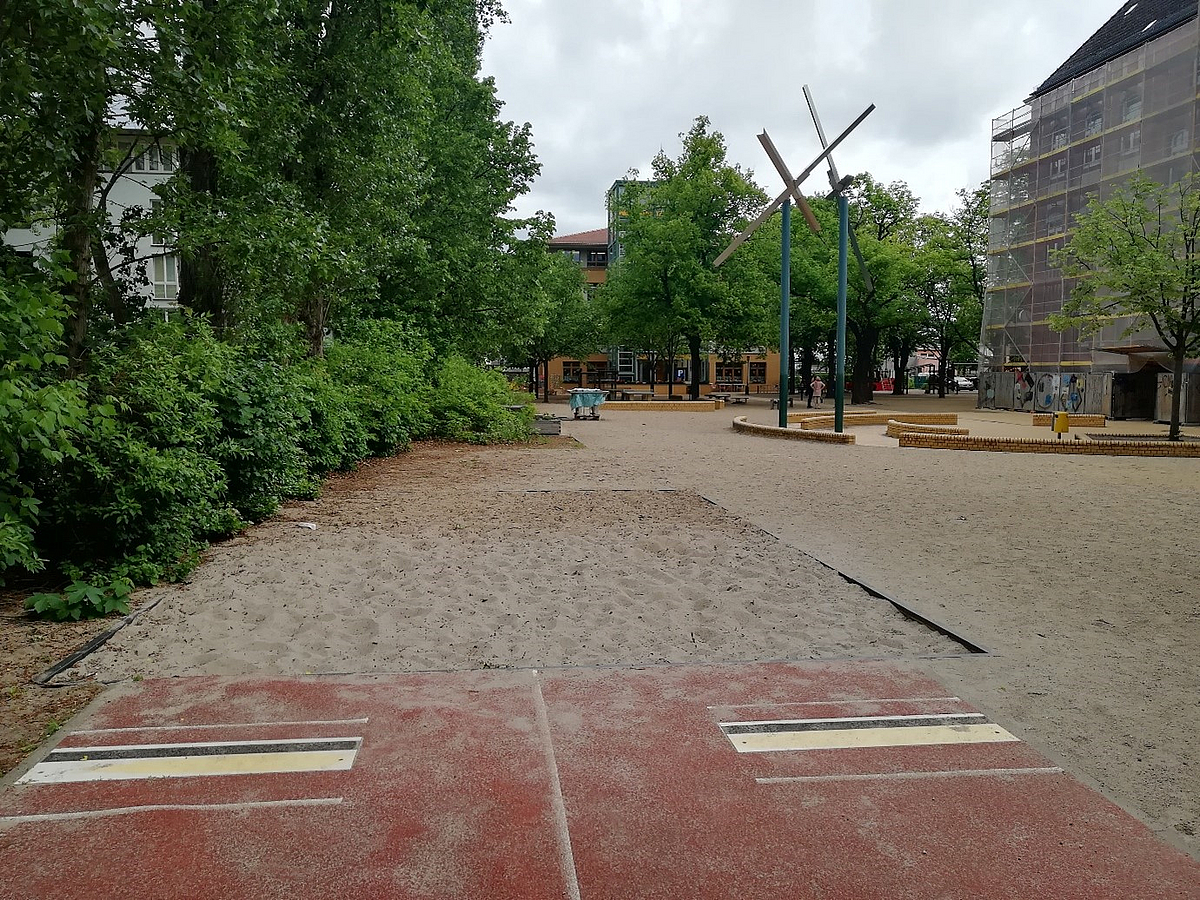 Schulhof, Weitsprunganlage und eingerüstetes, älteres Schulgebäude