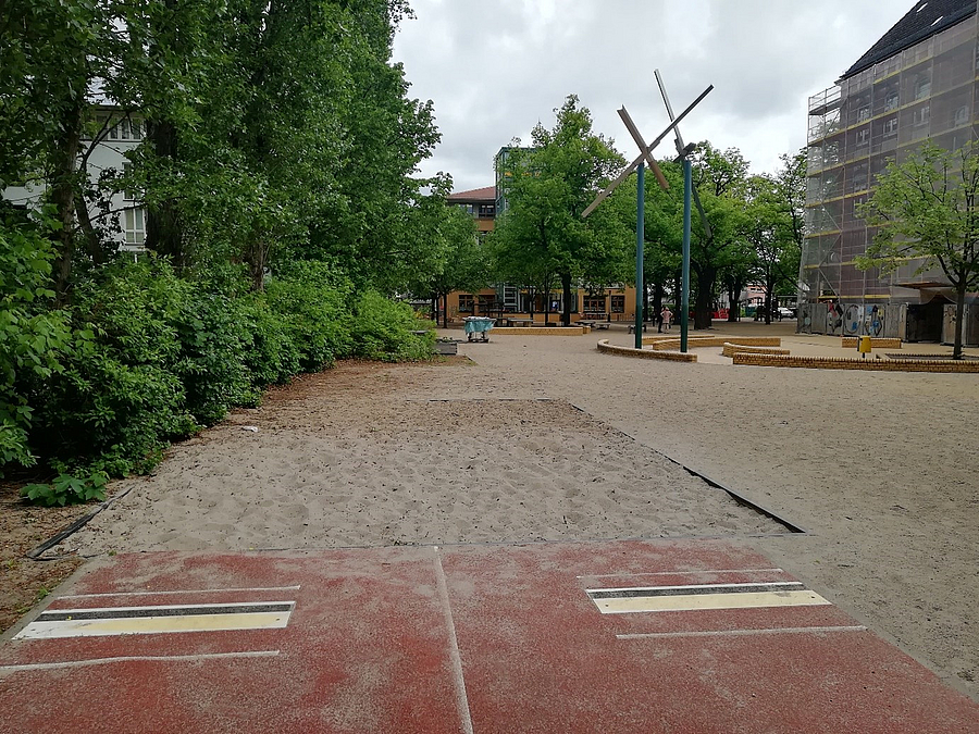 Schulhof, Weitsprunganlage und eingerüstetes, älteres Schulgebäude