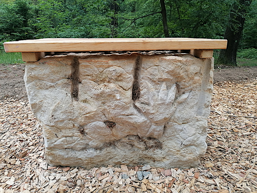Sandstein mit Gravuren, u.a. Tatze, Holzauflage zum Sitzen