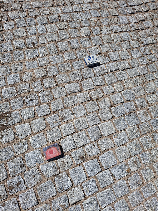 2 bemalte Keramik-Pflastersteine auf Pflaster gelegt