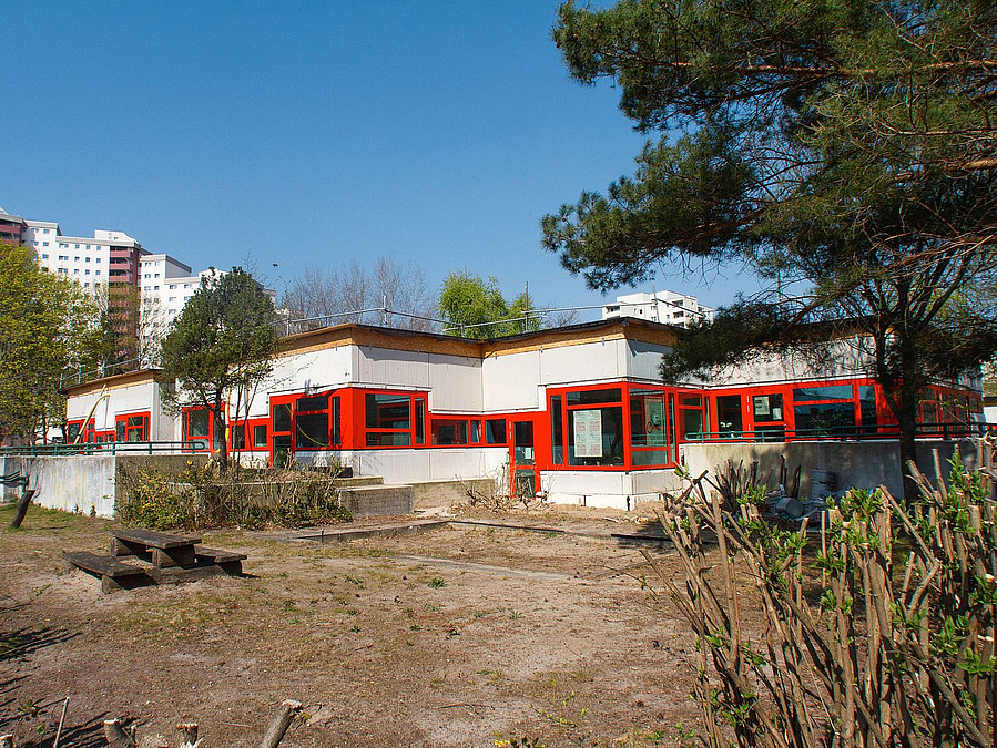 Mehrgliedriger Flachbau mit roten Fensterbändern