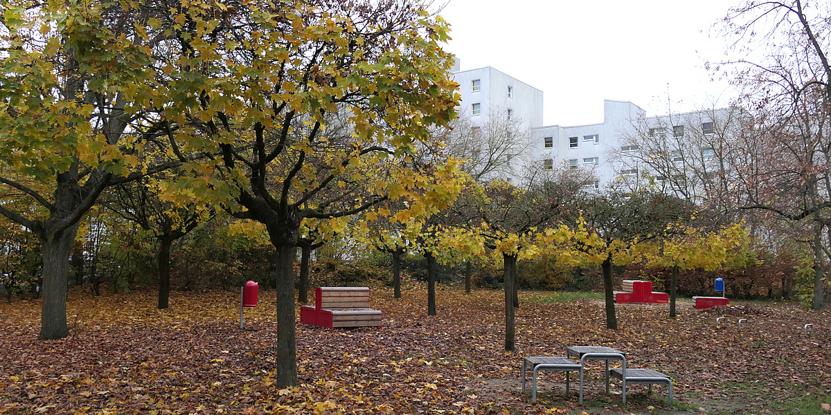 Herbstliche Laubbäume und verschiedene Sitzgruppen, teils in Rot