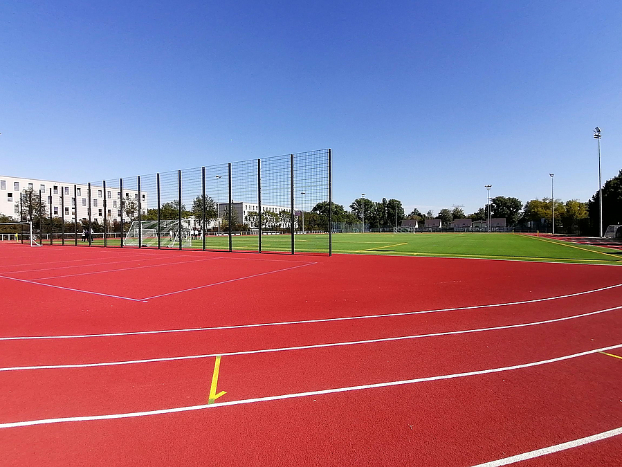 Blick aus Stadionkurve auf Ballfangzaun und Kunstrasenfeld