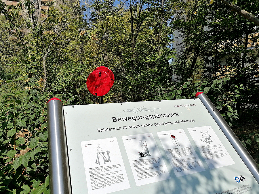 Schild mit Erklärungen, dahinter rotes Rad