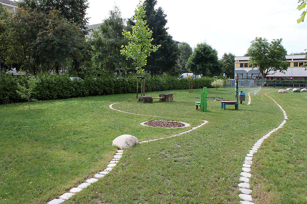 Weg über die Liegewiese vorbei an von Schülern gebauten Sitzgruppen auf der südöstlichen Freifläche