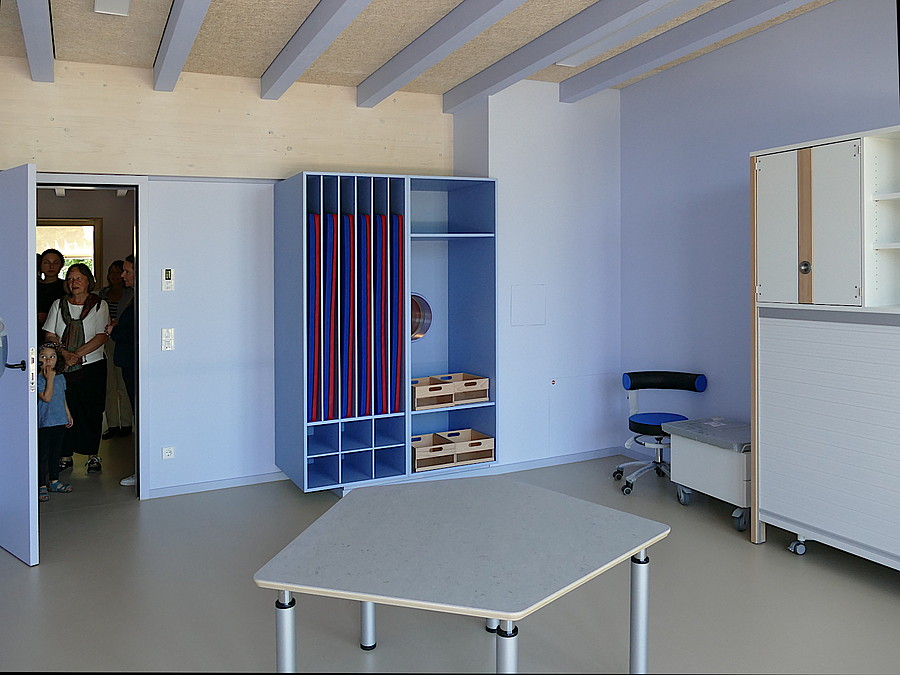 Raum mit blau-violetten Akzenten, Decke mit Balken, Regal mit Matten