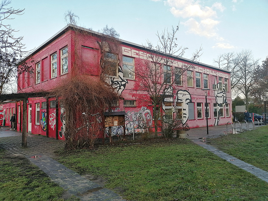 Rotes, zweistöckiges Gebäude mit Rankgewächs im Winter