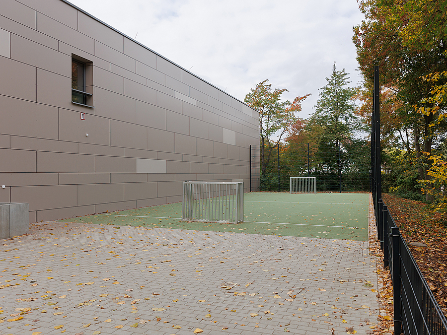 Graue Wand mit einem Fenster oben, daneben kleine Spielfläche mit Minitoren