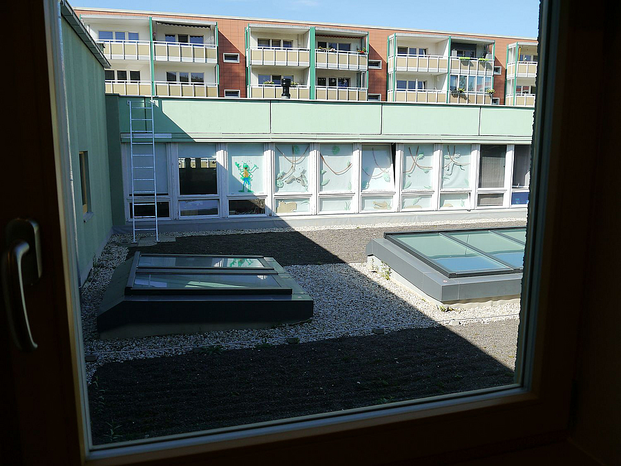 Dach mit Kiesbett, Oberlichtern, dahinter OG Bestandsbau mit Fensterband