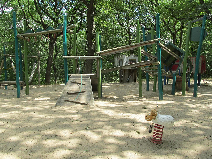 Sandfläche mit Wipptier, Kletterparcours aus Holz im Wald