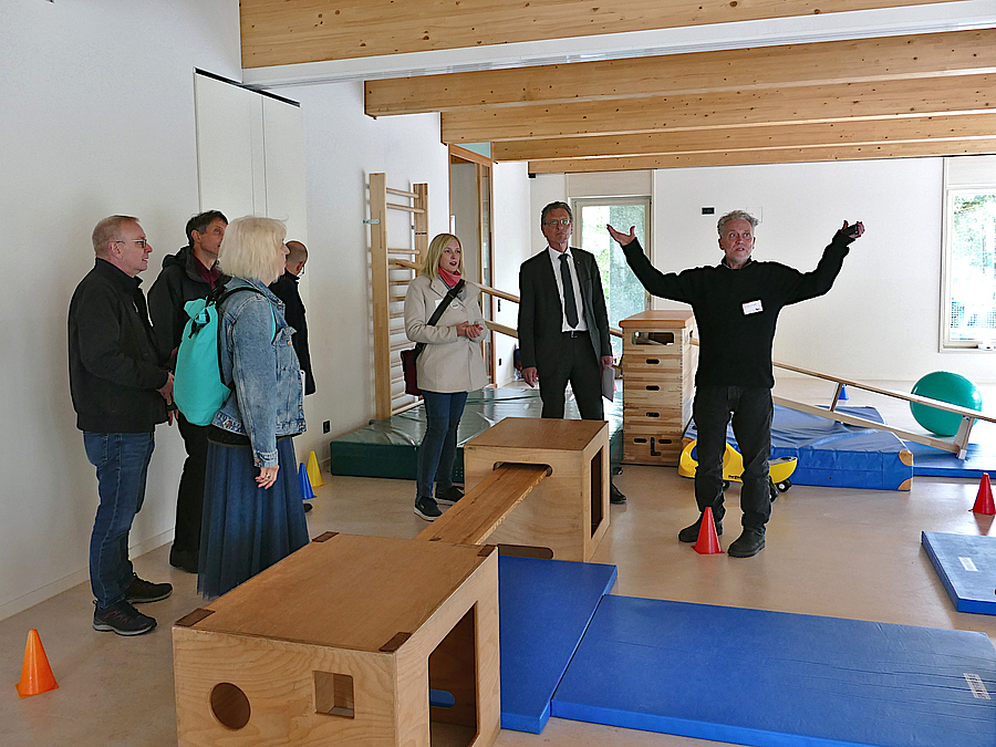 Gruppe bei Besichtigung eines Sportraums mit Holzbalkendecke