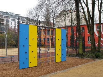 Kletterwand in Blau und Gelb auf Holzhäcckselfläche im Wohngebiet
