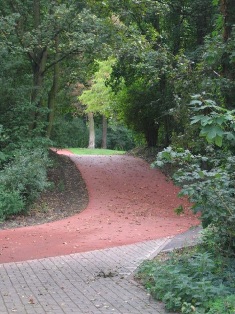 Roter Weg im Park mit Anschuss an anderen Weg