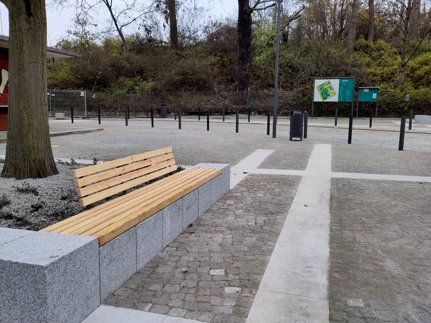 Baumscheibe mit Betonmauer und Sitzbank, Platz mit hellen Pflasterstreifen