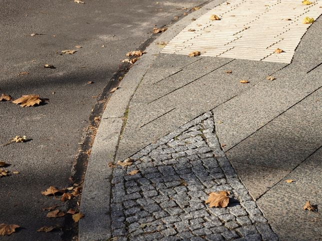 abgesenkter Wegrand mit Blindenaufmerksamkeitsstreifen, Kleinsteinpflaster und kleinen Platten